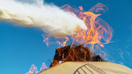 CLOSE UP: White powder extinguishes a pile of burning paper and cardboard.