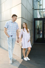 Young couple - man and woman expecting baby, spend time together on city street.