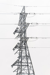 Electricity distribution system. High voltage overhead power line, power pylon, steel lattice tower standing in the field. Blue sky as a background.