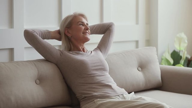 Happy middle aged woman relaxing sit on couch at home