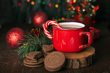 Christmas content, red mug with cocoa, marshmallow, Lollipop, wooden stand, chocolate cookies, spruce branch, red balls, lights, Christmas tree, dark background