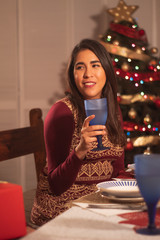joven mexicana brindando enfrente de árbol de navidad