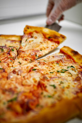 Slice of pizza on a spatula raised above a white table