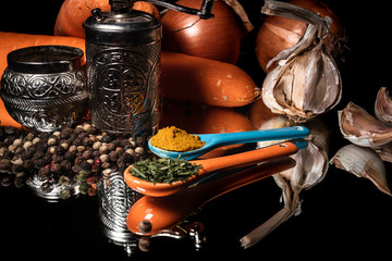 Old vintage pepper mill, pepper grains, spoons with spices and fresh organic vegetables with...