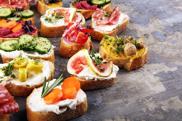 Assorted bruschetta with various toppings. Appetizing bruschetta or brie crostini. Variety of small sandwiches. Mix bruschetta on table