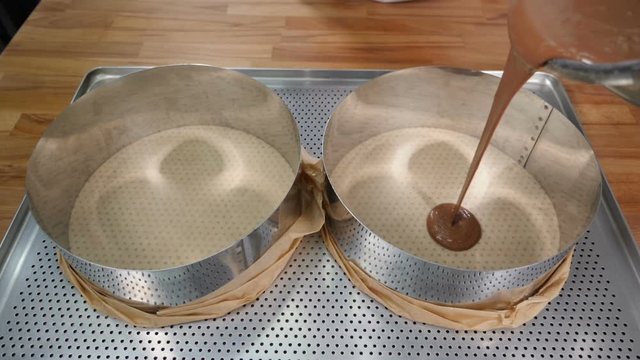 Pouring chocolate cake mixture into tins. Making Chocolate Layer Cake. Culinary concept. Slow motion. Shot in hd