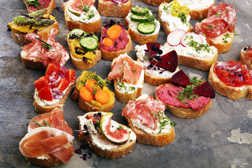 Assorted bruschetta with various toppings. Appetizing bruschetta or brie crostini. Variety of small sandwiches. Mix bruschetta on table