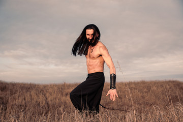 Young ukrainian man with long hair at the open steppe in Ukraine historical costume