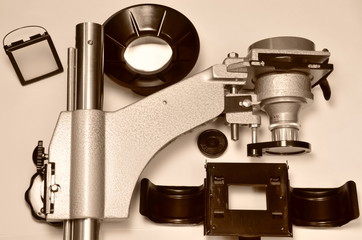 Components of the portable enlarger UPA-4m since late 60's, for 35-mm b&w printing. Old soviet enlarger with the accessories laid out on the table (sepia)
