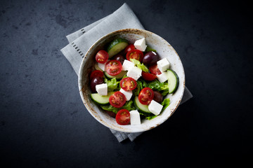 Salad with Kalamata Olives, Cucumber Cherry Tomatoes and Feta Cheese on black Stone Background. Healthy Snack Idea. Top view. Copy space. 