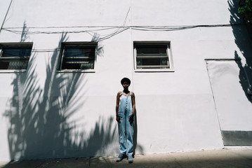 Portrait of woman wearing coveralls standing in front of building