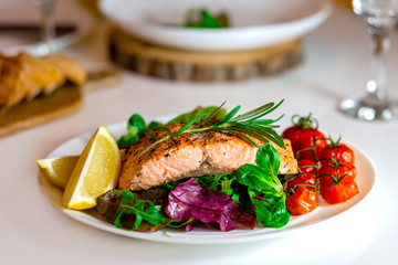 Salmon steak with lettuce, cherry tomatoes and lemon slices. Gala dinner. Food for lunch. Grilled red fish. Baked salmon in the oven