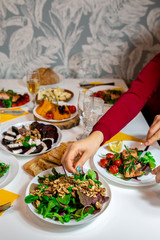 Salmon steak with arugula and vegetables. A feast with people. Beautiful canned white table with food. Festive dinner. Family at the table. Food for lunch