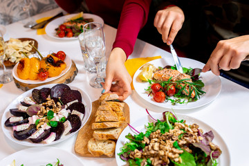 Salmon steak with arugula and vegetables. A feast with people. Beautiful canned white table with food. Festive dinner. Family at the table. Food for lunch