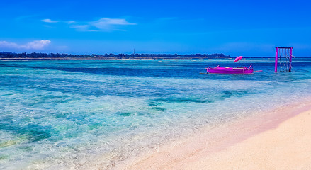 Gili Air, Lombok, Indonesia - Pink boat on the beach with umbrella next to wooden water swing in the Gili islands. Popular instagram location and holiday destination in Indonesia.