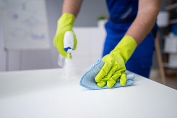 Man Cleaning The Glass Office Desk With Rag