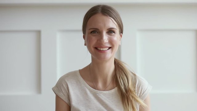 Smiling young woman talking video calling online looking at camera