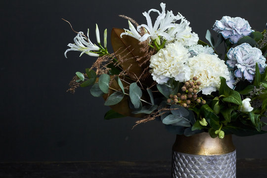 White toned bouquet in vintage style in a ceramic vase on a dark background, selective focus