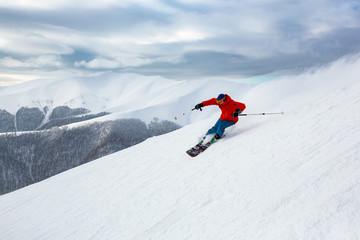 A skier in the red jacket is riding fast.