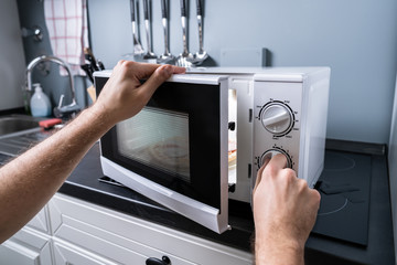 Man Preparing Food In Microwave Oven