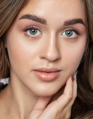 Portrait of a beautiful happy woman with long eyelashes, beautiful fresh nude make-up, thick eyebrows and with clean skin in a beauty salon. Eyelash extensions. Face close-up. Make-up concept