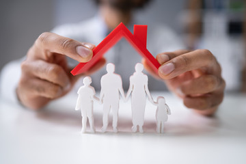 Person Protecting Family Figures With Roof