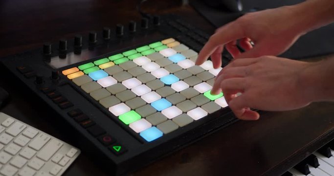 An electronic dance music producer making a beat in his bedroom studio with a digital instrument midi controller.