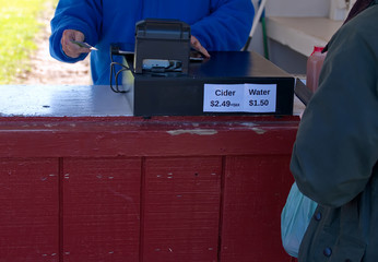 Water and cider price signs on a cash register at an orchard outdoor checkout stand stand.