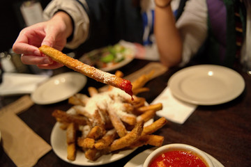 A unique and delicious serving of hot and oily eggplant french fries being dipped in sauce.