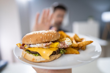 Man Refusing Burger Offered By Person
