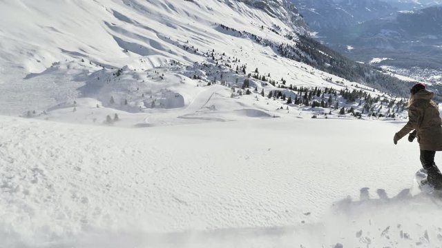 A girl is snowboarding in the backcountry during the winter in Swiss Alps. Shot in 4k with a gimbal.
