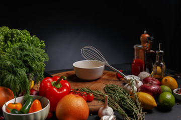 Metal whisk for whipping on a wooden board with different ingredients for cooking.