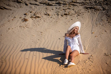 girl in white clothes sitting on the sand