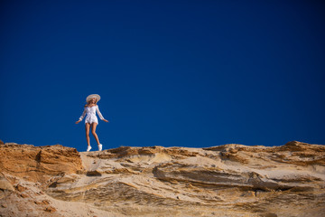attractive blond girl in white stands on the beach. 