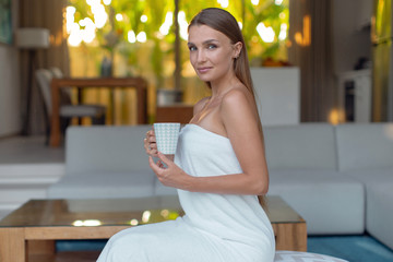 Young beautiful girl with a cup of tea in the morning after spa