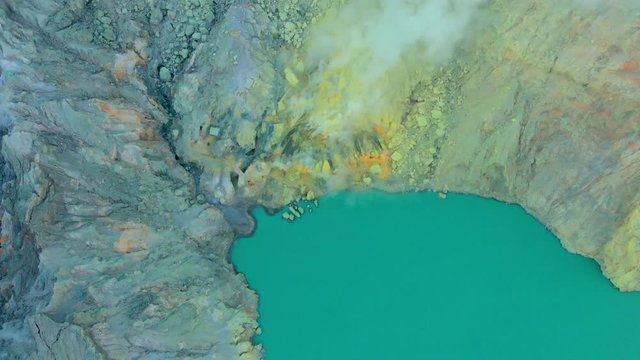 Aerial shot. Sunrise at a famous active Ijen volcano or Kawah Ijen on the Java island. Its crater is filled with the biggest in the world acid lake. And there is a sulfur mine where volcanic gasses go