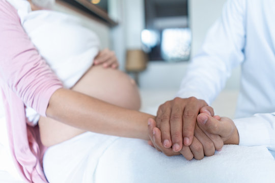 The doctor hand holding pregnant belly woman client and trust encourage the patient and take care.