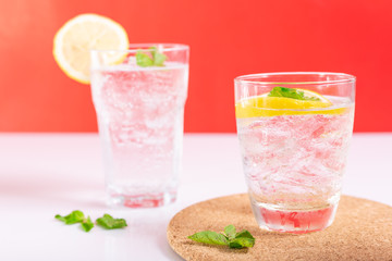 Lemon soda drink cocktail with mint, lemonade, on white and red background