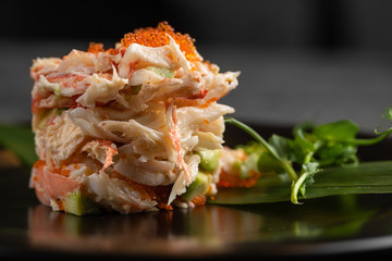 Olivier with crab meat in a beautiful bowl in the form of oysters, on a dark background © sutulastock