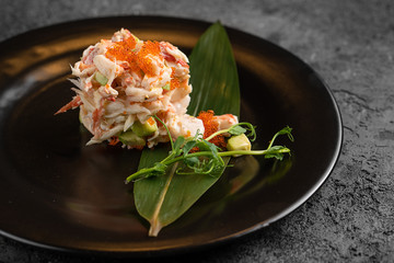 Olivier with crab meat in a beautiful bowl in the form of oysters, on a dark background © sutulastock