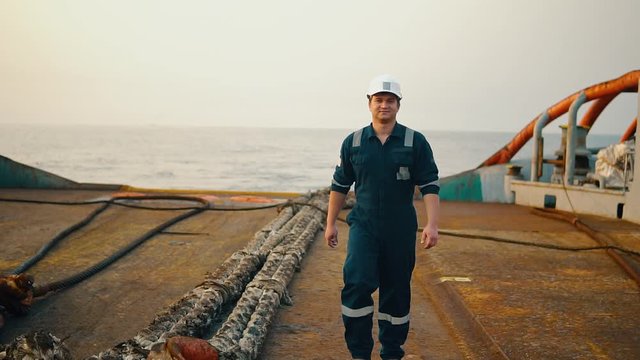 Marine Deck Officer or Chief mate on deck of offshore vessel or ship , wearing PPE personal protective equipment - helmet, coverall. He is looking at the camera