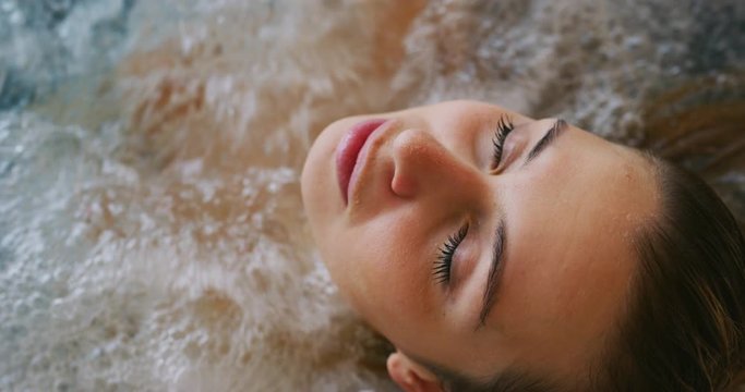 Close up of an young female is enjoying and having relax in a bath tube in a luxury wellness center.