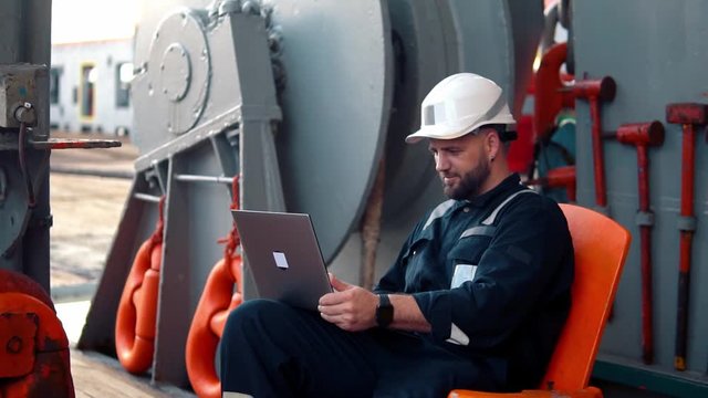 Marine chief officer or captain on deck of vessel or ship watching laptop. Internet and home connection at sea.