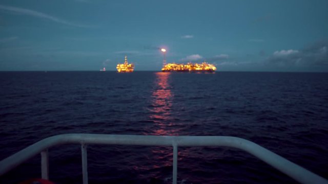 FPSO tanker vessel near Oil Rig platform. Offshore oil and gas industry. Flare is burning with smoke. View from supply vessel.