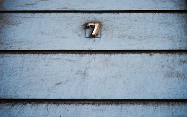 Number 7, seven, on subdued pale blue wall with horizontal black lines, vintage effect.