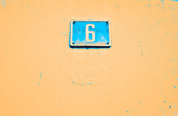 Number 6, six, blue plate on pale orange background.