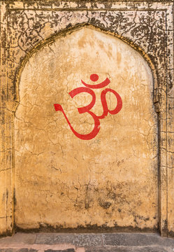 An old textured indian fort wall with an arch and OM symbol painted on the wall.