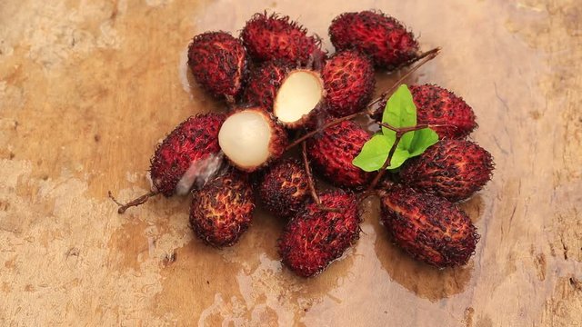 Fresh lychees in white ceramic dish on a wooden table.