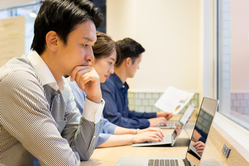 長テーブルで並んで仕事をする男性と女性