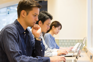 長テーブルで並んで仕事をする男性と女性